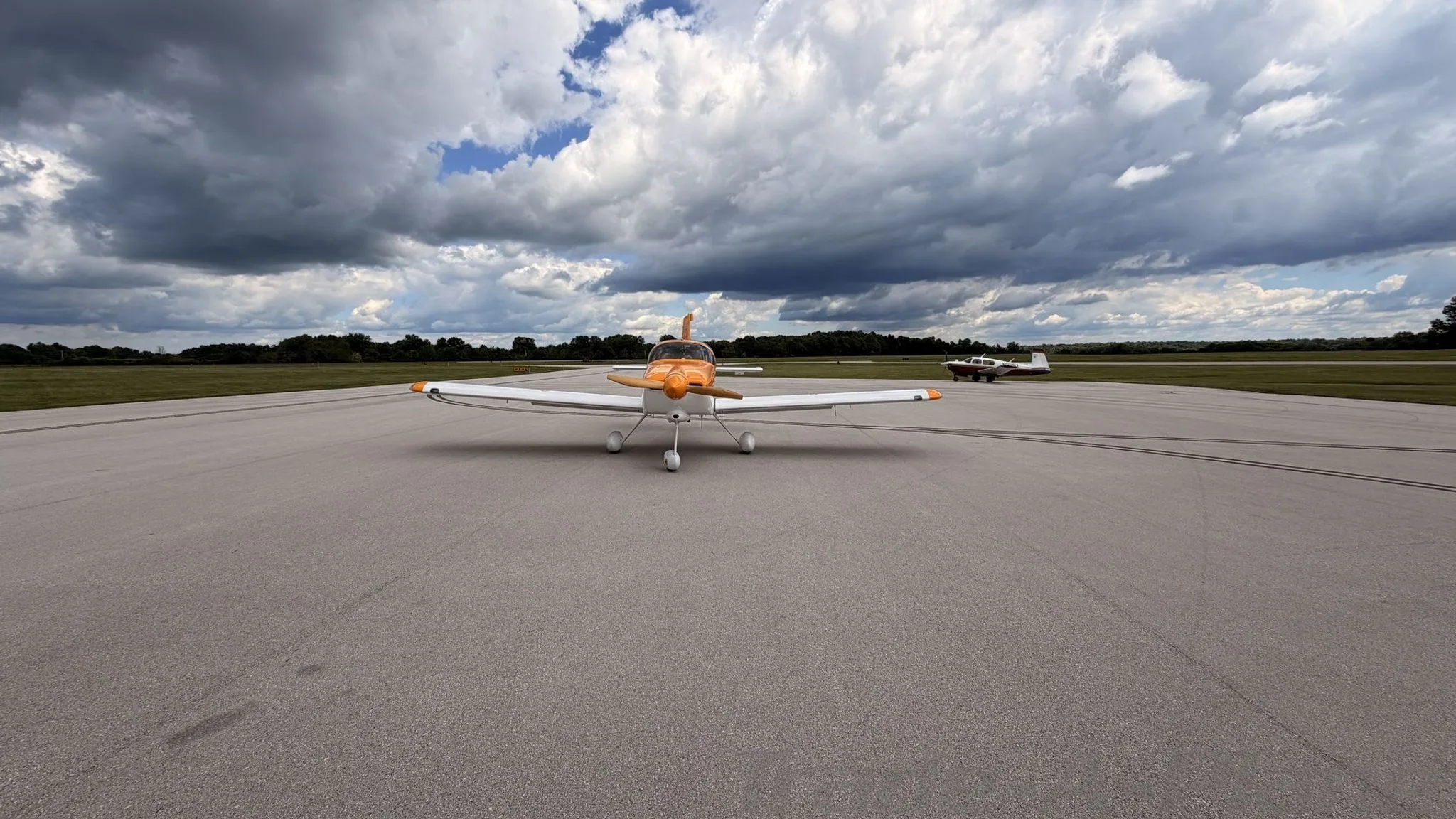A front view of the aircraft on the runway with another plane in the background.