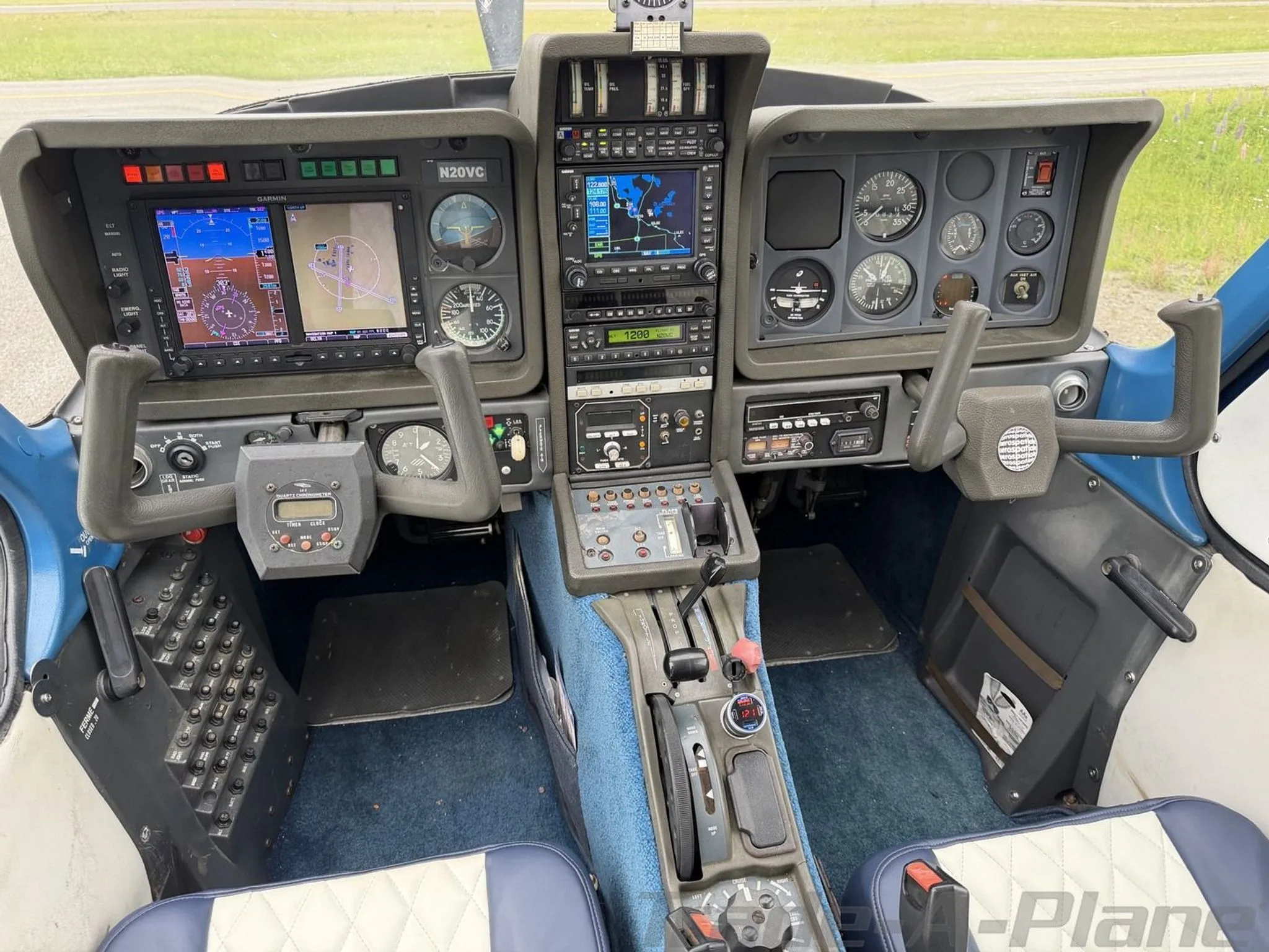 A detailed view of the N20VC aircraft's cockpit, showing the instrument panel with multiple displays and controls, and blue carpet.