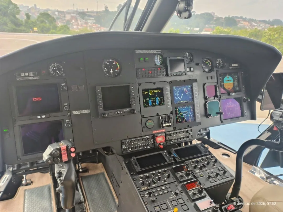 The cockpit of a helicopter features multiple digital displays and control panels.