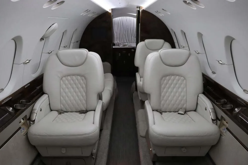 The aircraft's cabin interior featuring light grey quilted leather seats arranged in a club configuration.