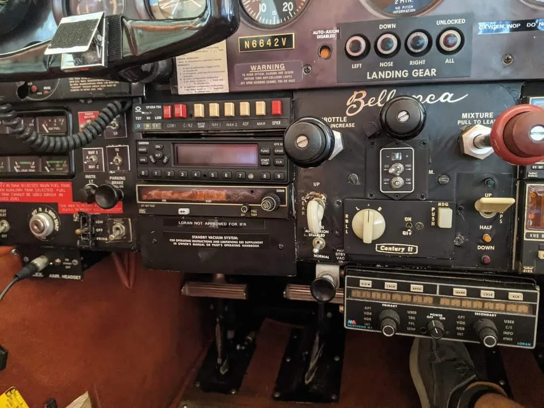 A detailed view of the Bellanca aircraft's instrument panel, showing radios, controls, and pedals.