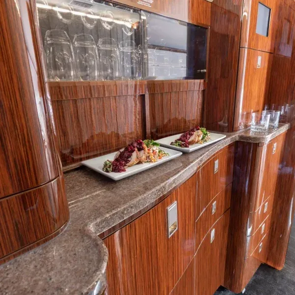A private jet galley with dark wood cabinetry, a stone countertop, and two plated meals.