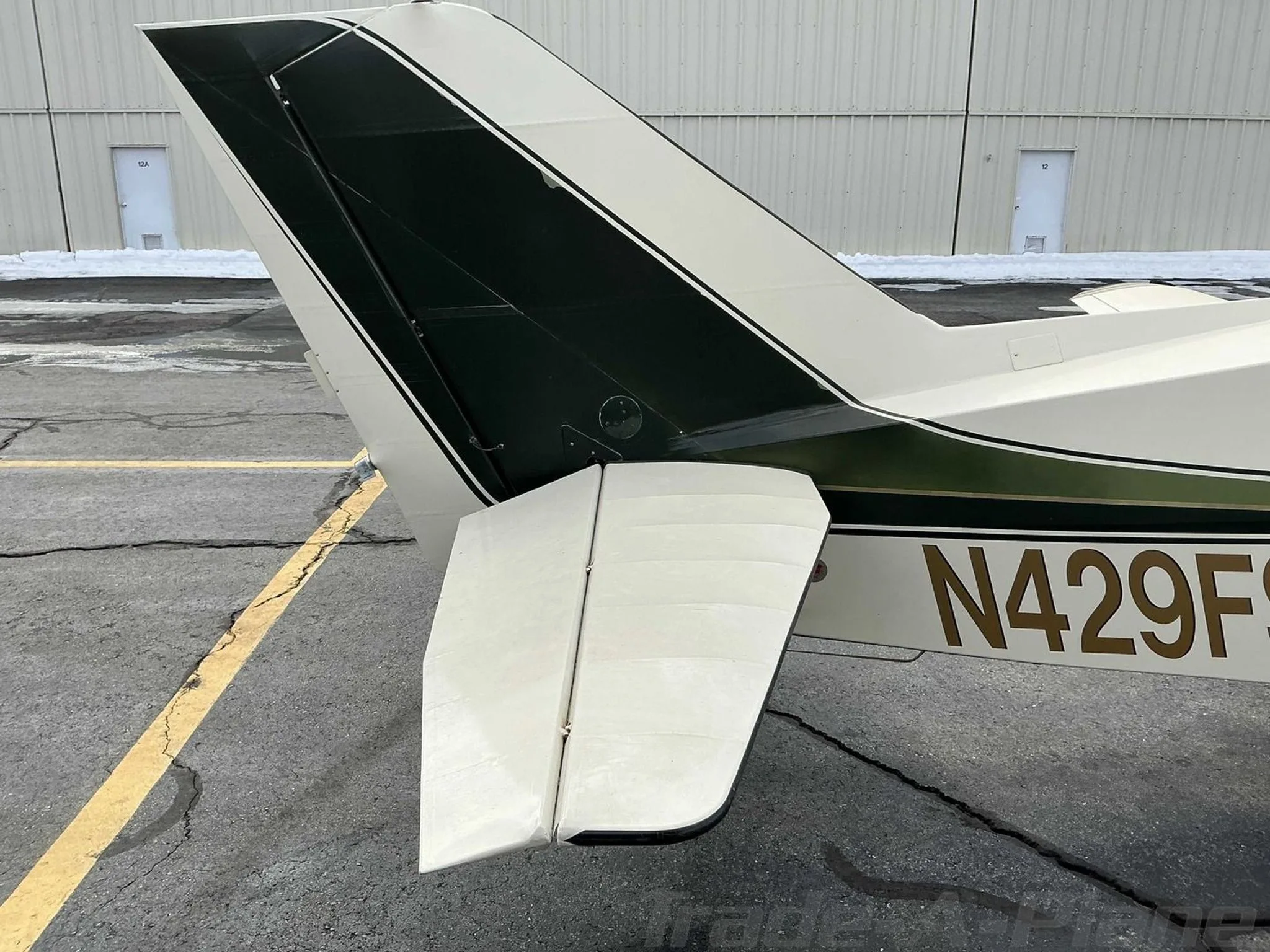 A close-up view of the tail of the Bellanca Viking aircraft, N429FS, showing its green and white paint scheme.