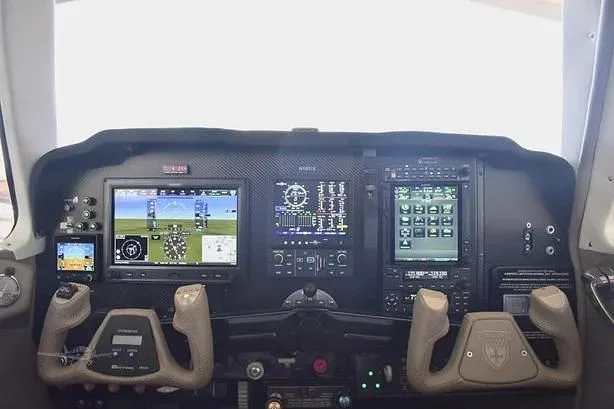 The aircraft's cockpit instrument panel featuring multiple digital displays and control yokes.