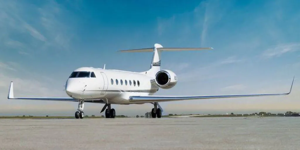 A white Gulfstream G550 business jet parked on a tarmac, viewed from the front-right.