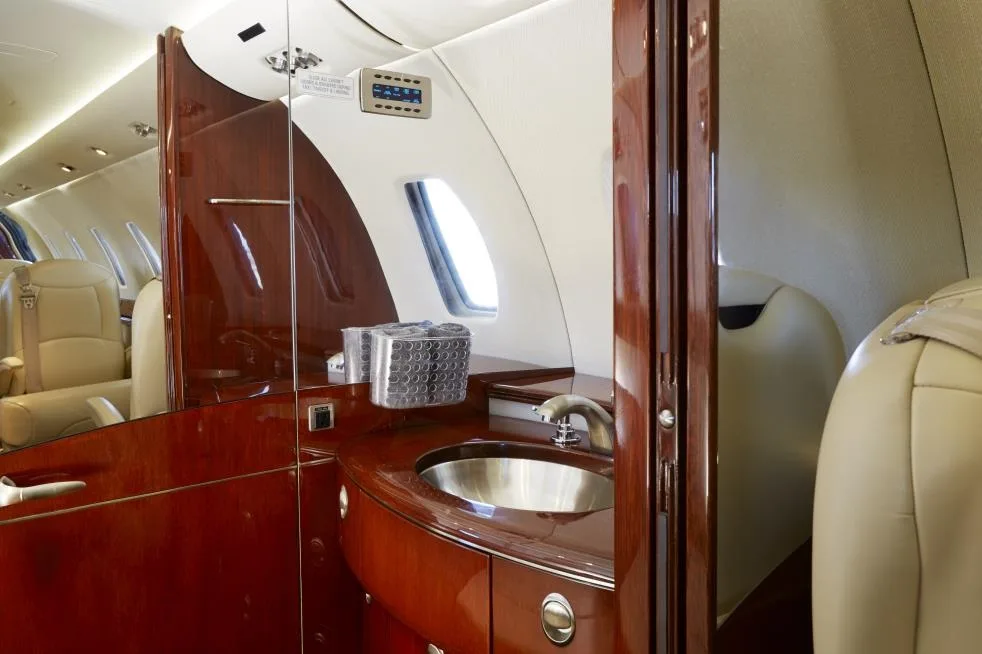 A view of the aircraft lavatory with wood trim and a sink.