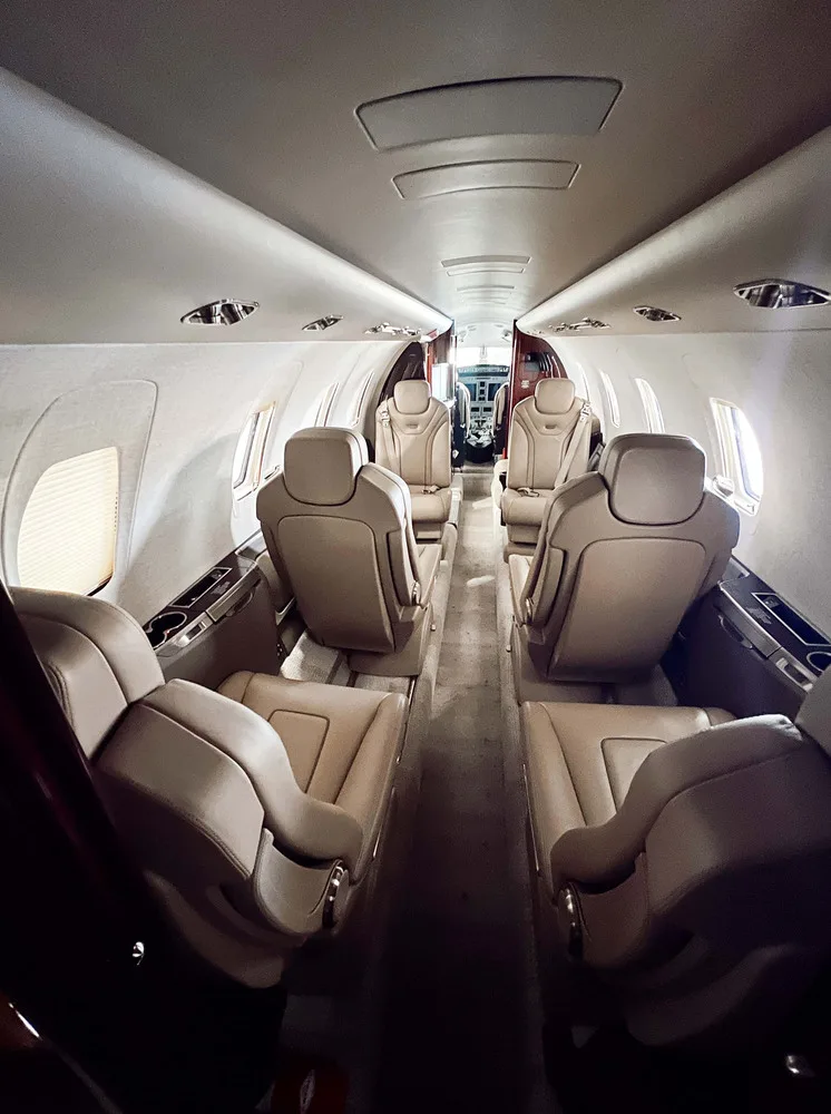 A long view down the aircraft's cabin, showing multiple rows of tan leather seats.