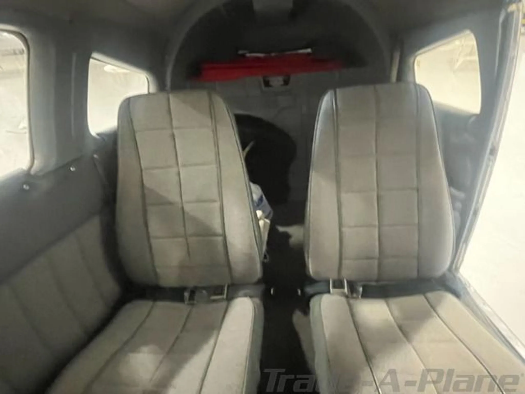 The aircraft's gray interior cabin shows two rear seats facing forward.