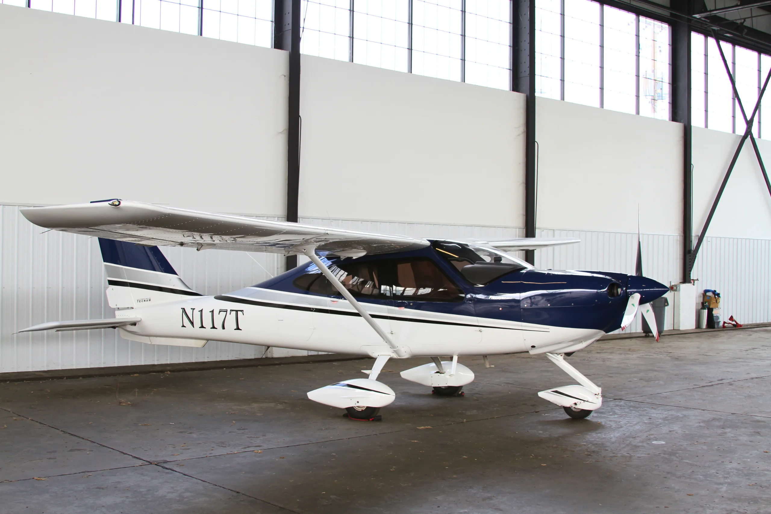 A white and blue Cessna aircraft is parked inside a hangar.