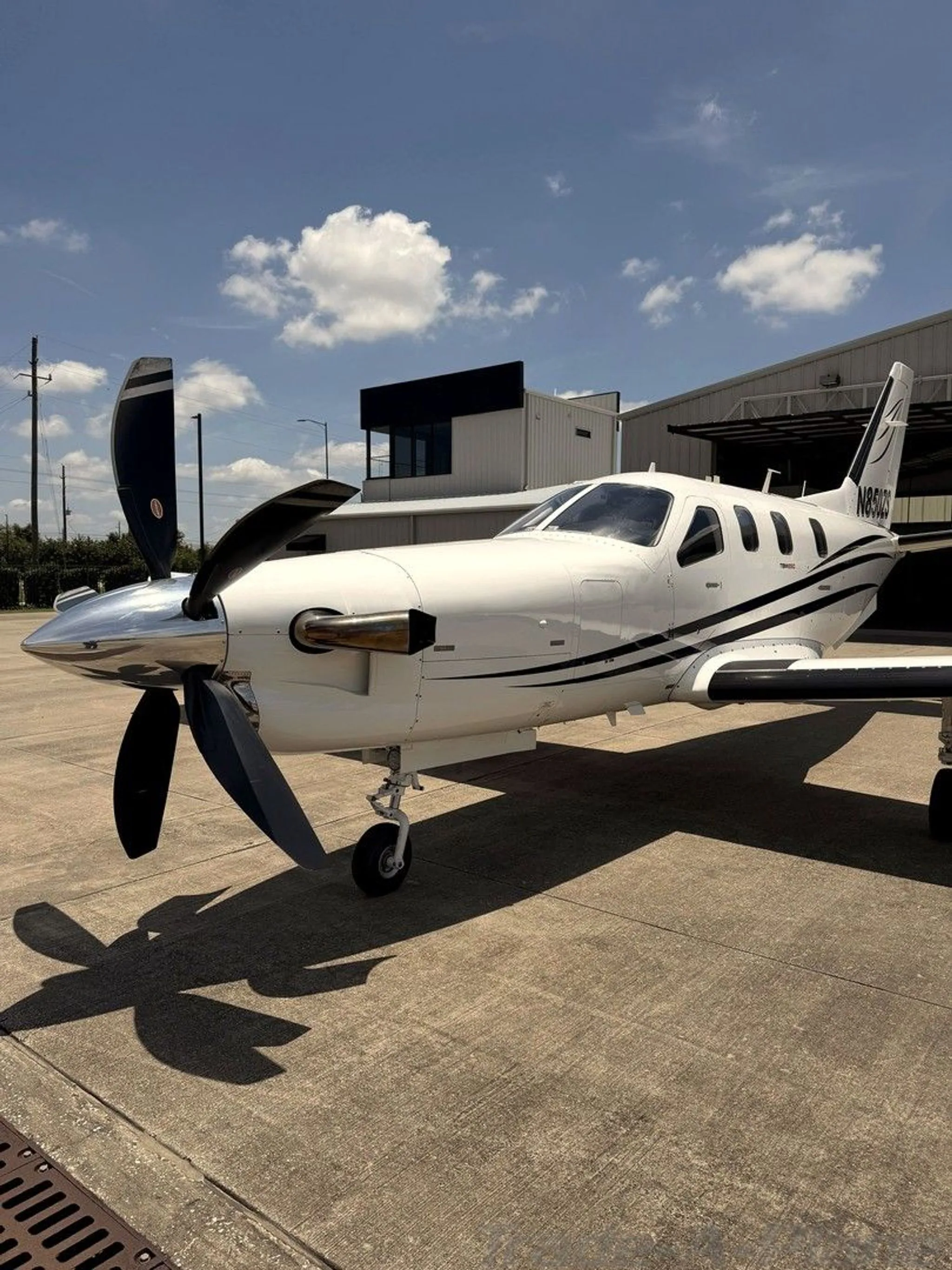 Side view of a white turboprop aircraft with black stripes and registration N850ZS parked on an airfield.