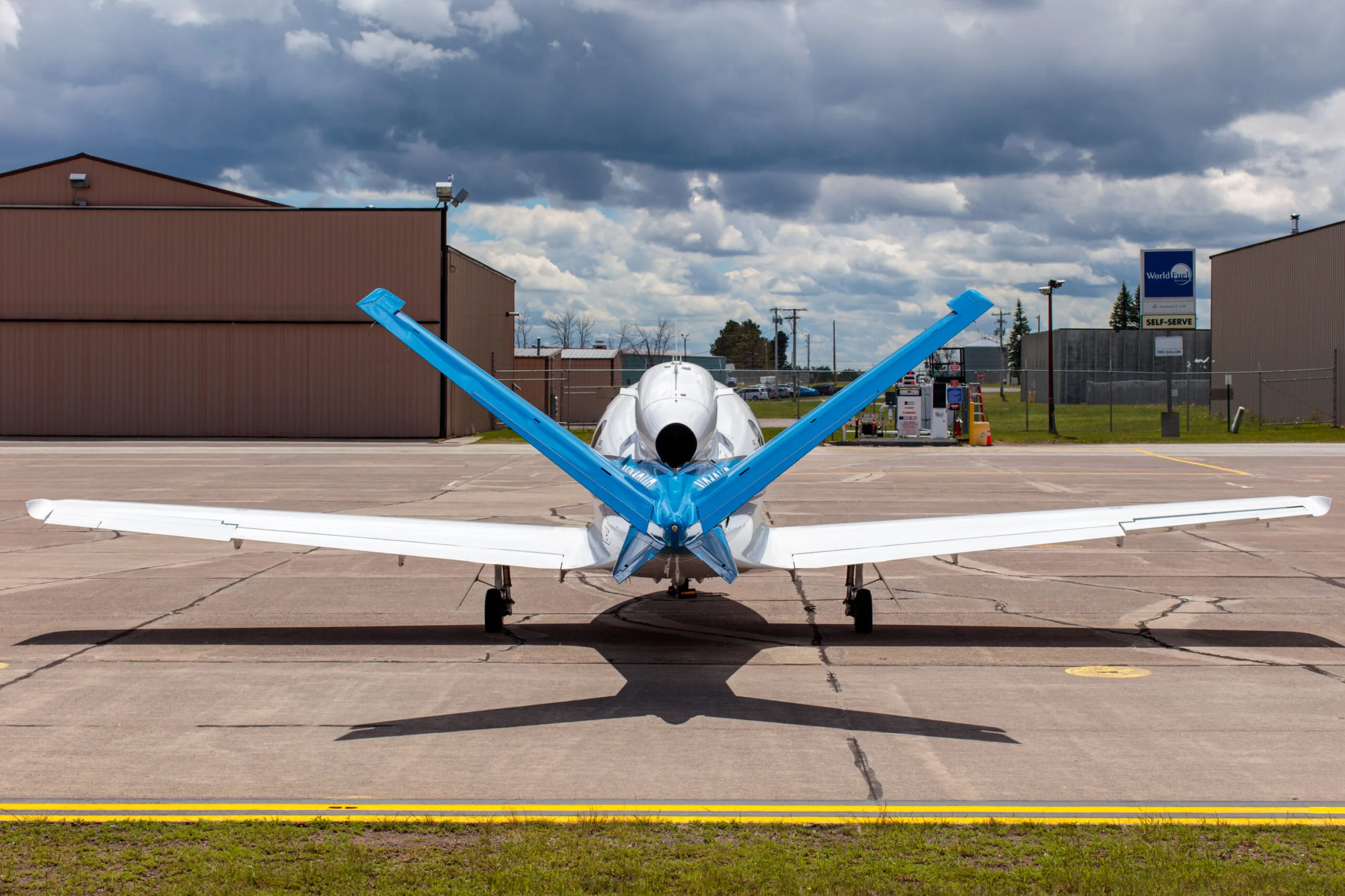 Rear view of a white and blue Cirrus Vision Jet (N218HP) showing its V-tail and engine exhaust.