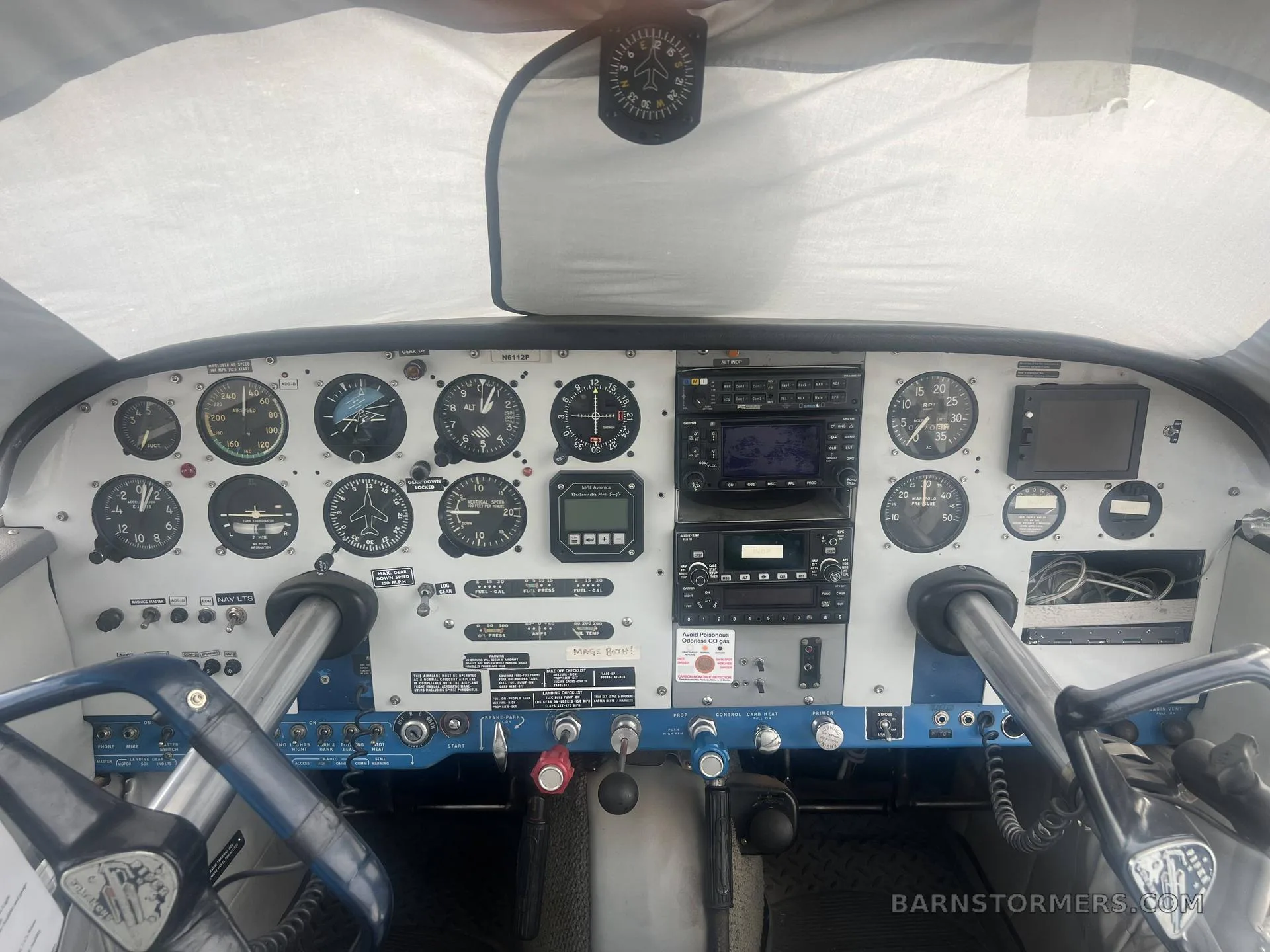 The cockpit of a small aircraft, showing the instrument panel with various gauges, radios, and control yokes.