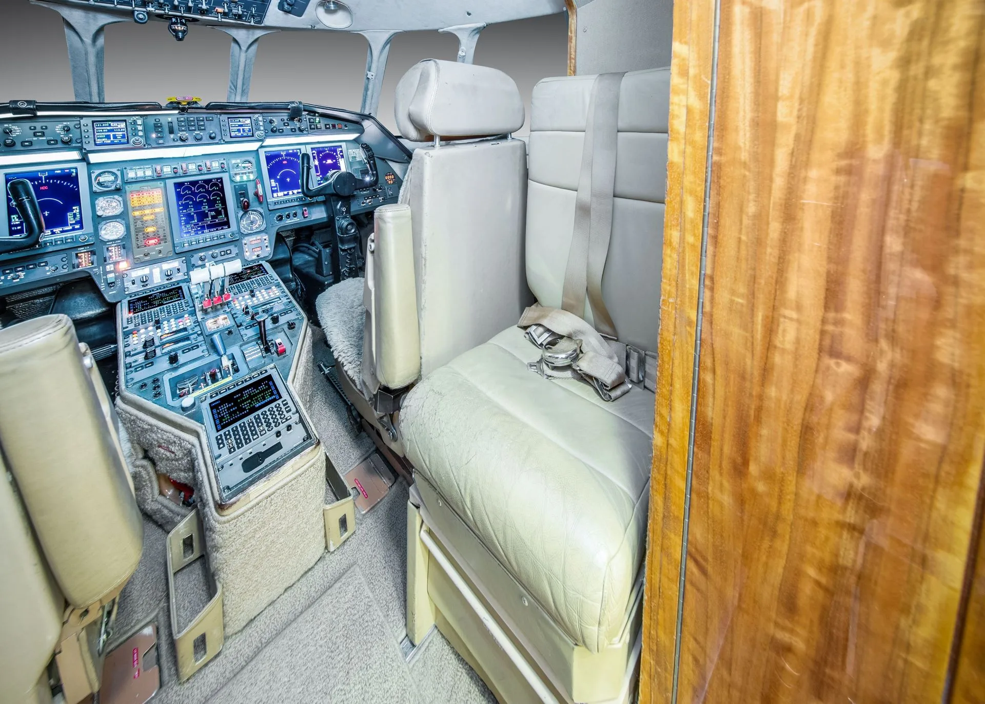 A view of the aircraft cockpit from the side, showing the pilot's seat, instrument panel, and a jump seat.