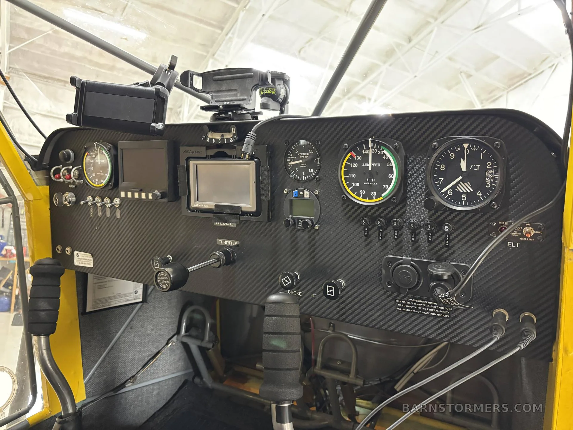 The carbon fiber instrument panel of a small aircraft, featuring analog gauges and a digital display.