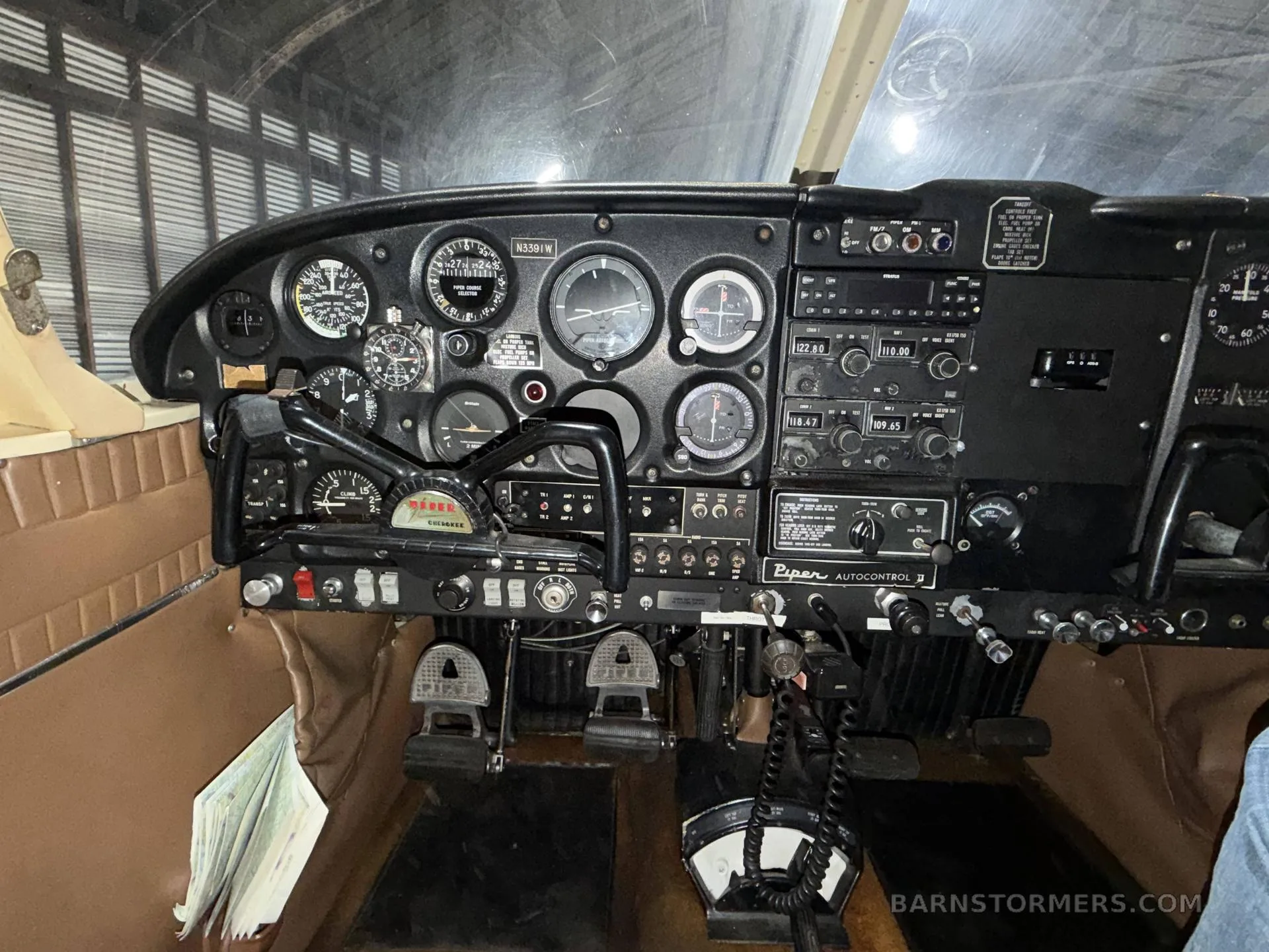 A close-up view of the instrument panel and controls of a Piper aircraft, showing various gauges and avionics.