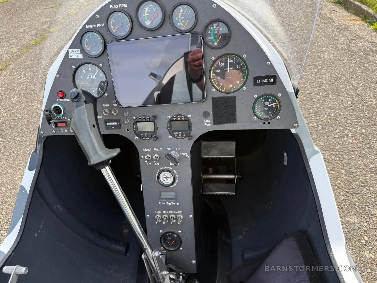A close-up view of the MTO Sport gyrocopter's instrument panel, featuring analog gauges, a digital display, and flight controls.