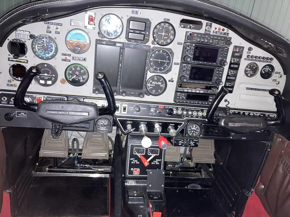 The full cockpit of the Grumman American AA-5B Tiger, N267MT, showing the instrument panel, yokes, and rudder pedals.
