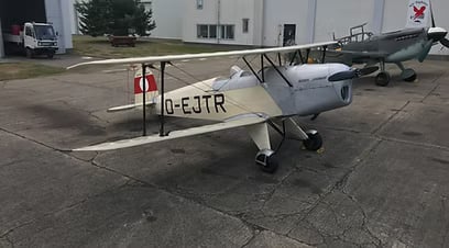 Side view of the D-EJTR Bucker Jungmann biplane parked on the tarmac.