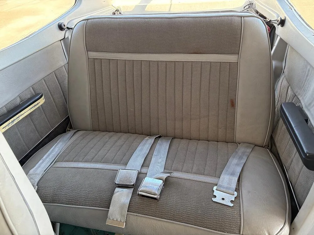 The gray fabric and vinyl rear seats of a Cessna aircraft, with seatbelts buckled.