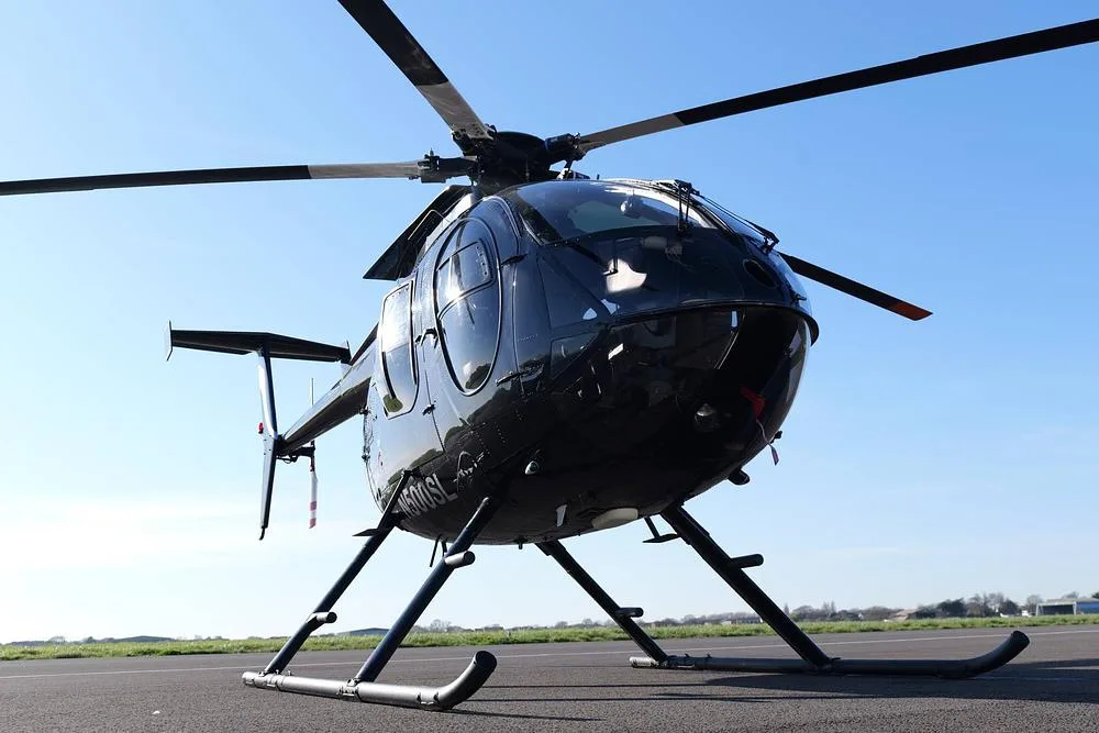 A close-up front view of a black MD 500 helicopter (N500SL) parked on an airfield.
