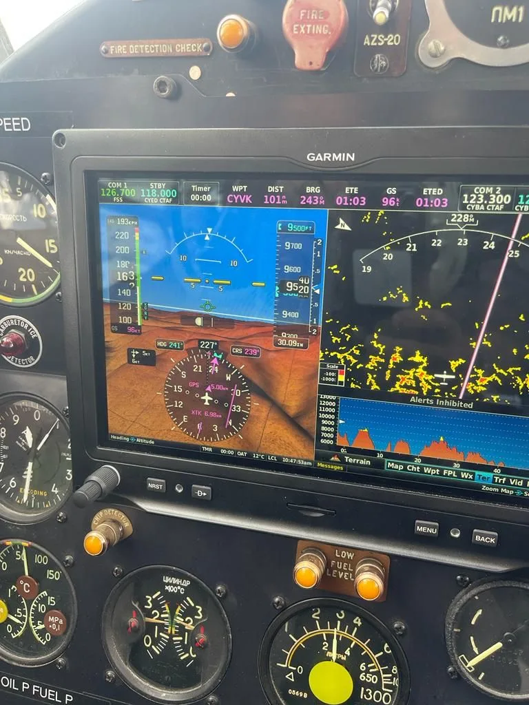 A close-up of a Garmin navigation display in the Antonov AN-2 cockpit, showing flight data and terrain.