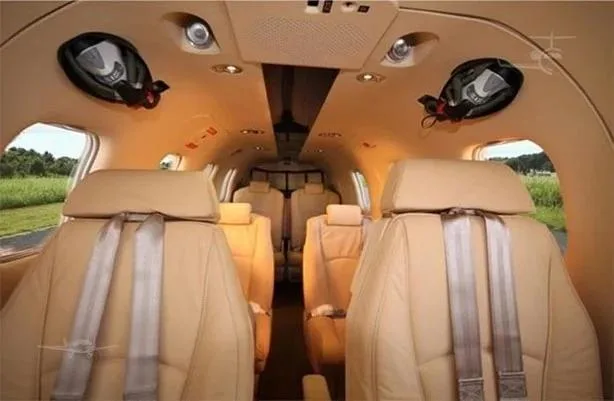 A view of the aircraft's interior cabin with rows of light tan leather seats and overhead lighting.