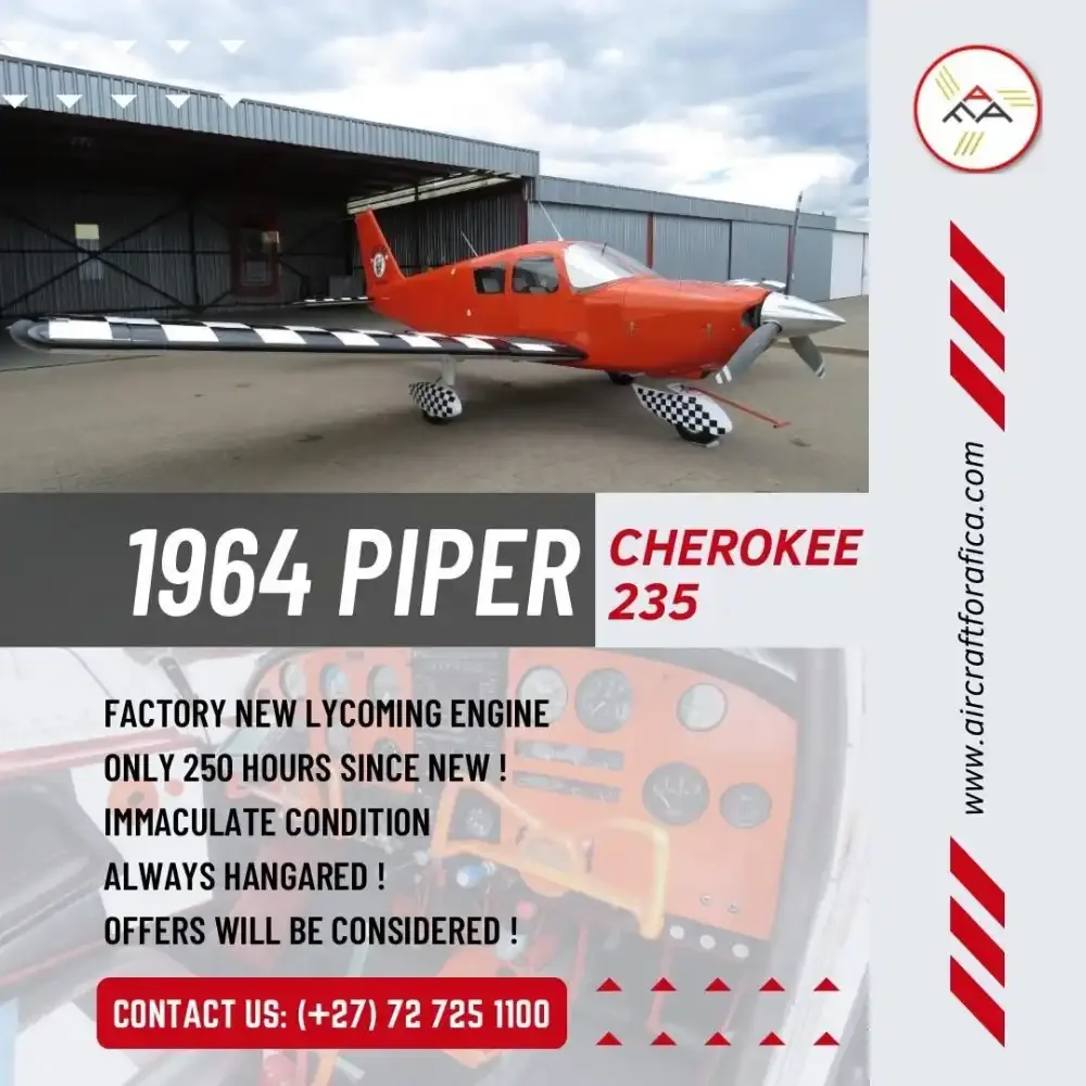 A red 1964 Piper Cherokee 235 with checkered wings and wheel fairings, parked outside a hangar.