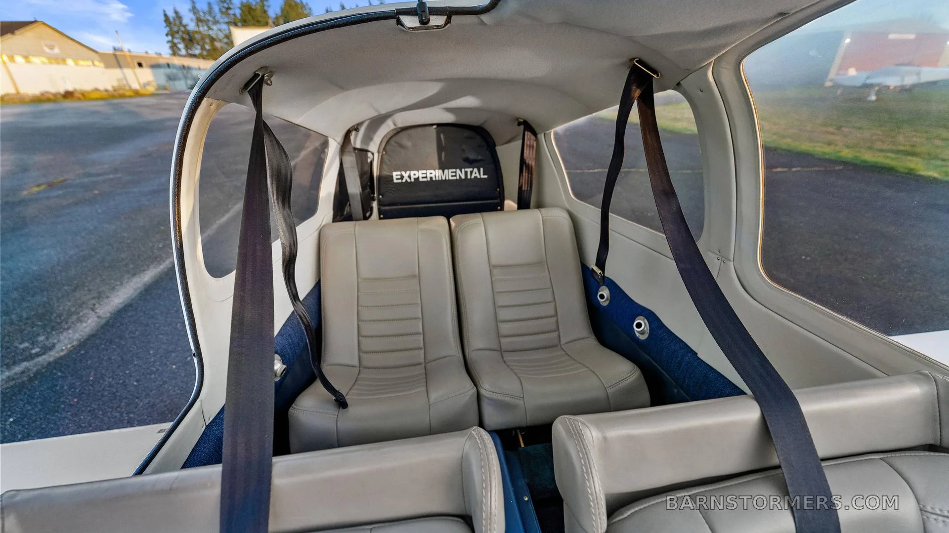 The light gray interior cabin of the aircraft, showing two rear seats with "EXPERIMENTAL" visible on a bag in the back.