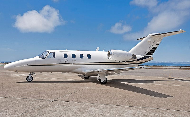 A white jet aircraft with black stripes is shown parked on the tarmac.