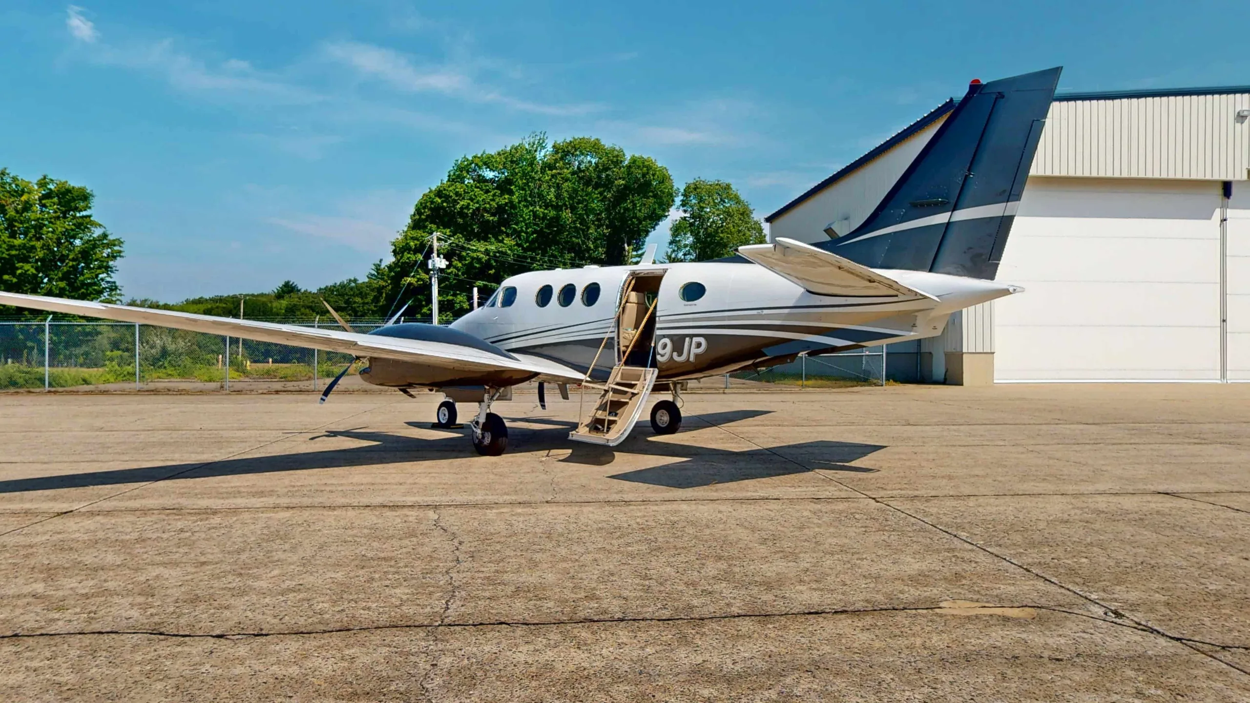 King Air aircraft parked on the tarmac with the door open and stairs extended.
