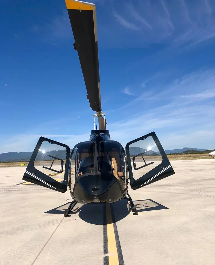 Front view of a black helicopter with open doors on the tarmac.