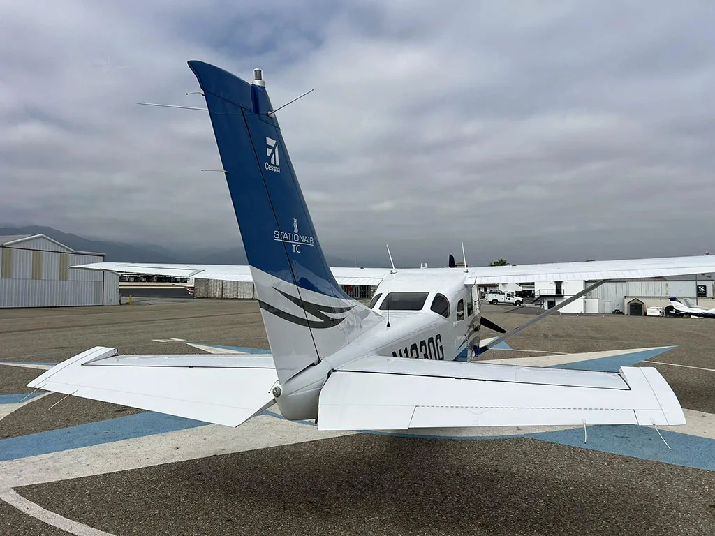 Rear view of a white and blue Cessna Stationair TC (N1330G) with its tail and horizontal stabilizers prominent.
