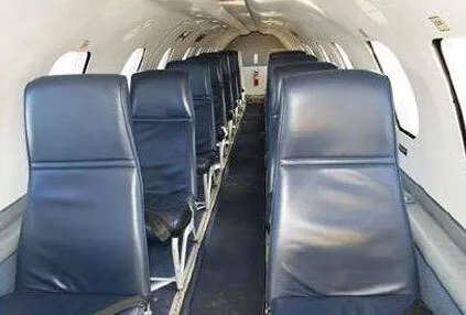 The interior cabin of an aircraft with rows of blue passenger seats.