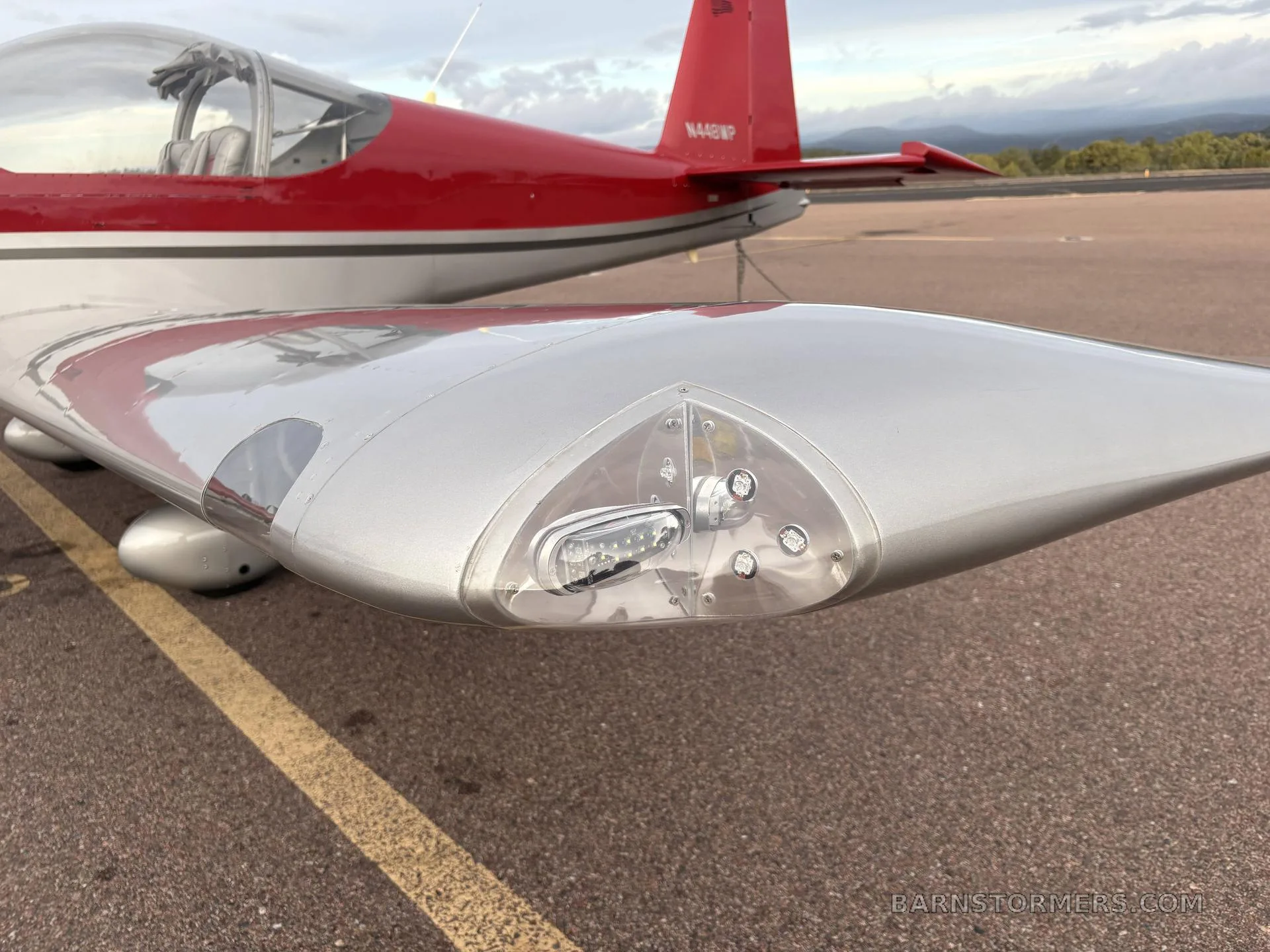 A close-up view of the silver wingtip of aircraft N448WP, showing the navigation and landing lights.