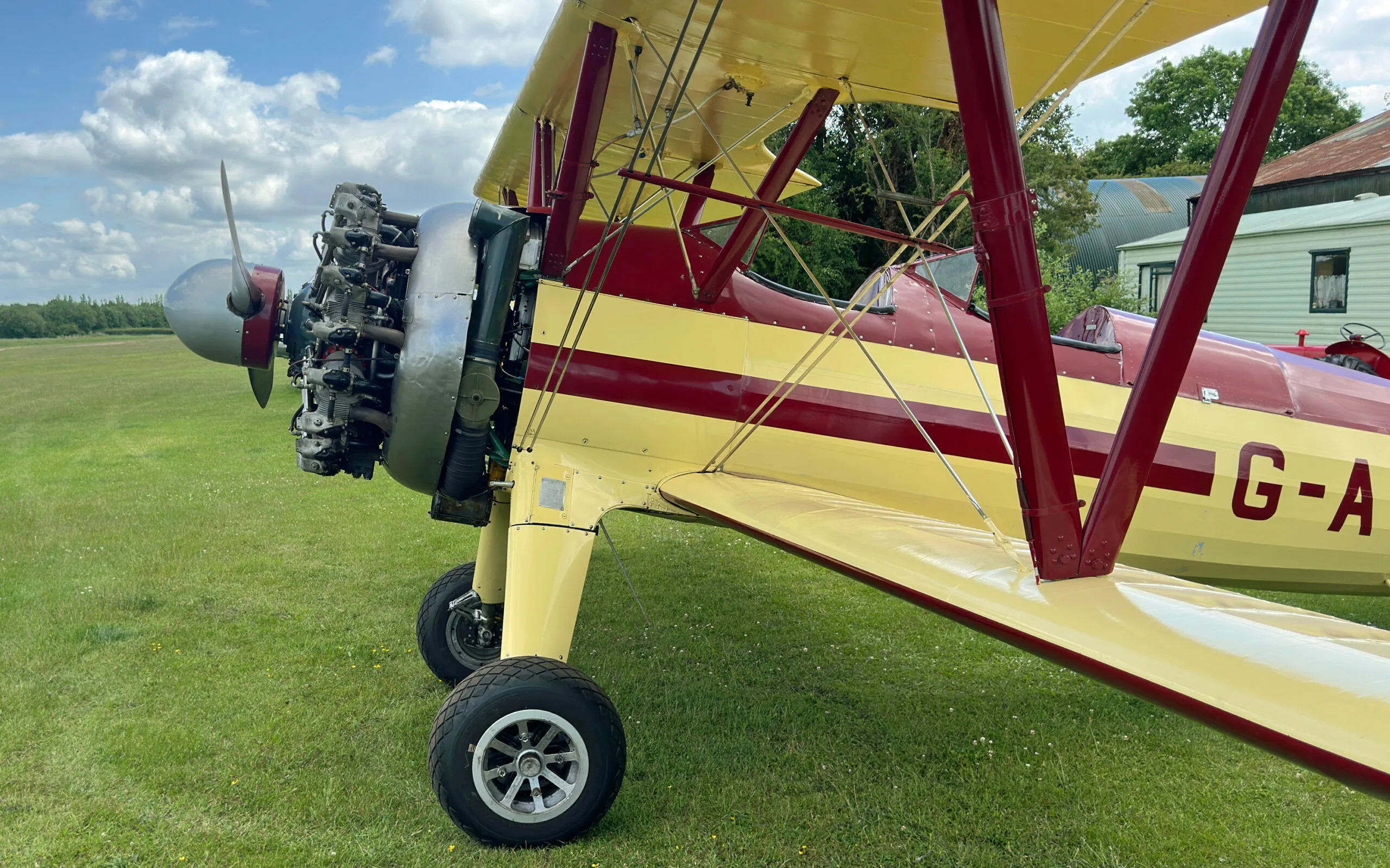 A close-up view of the radial engine and front landing gear of the yellow and red Stearman biplane.