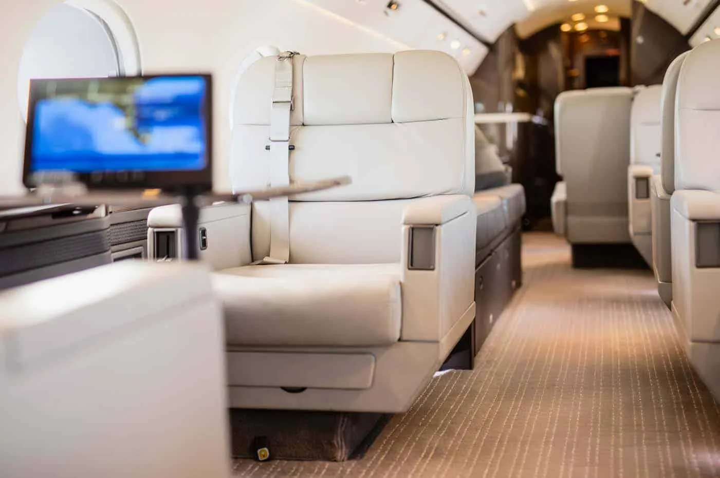 A close-up view of light-colored leather aircraft seats with a screen displaying a map in the foreground.