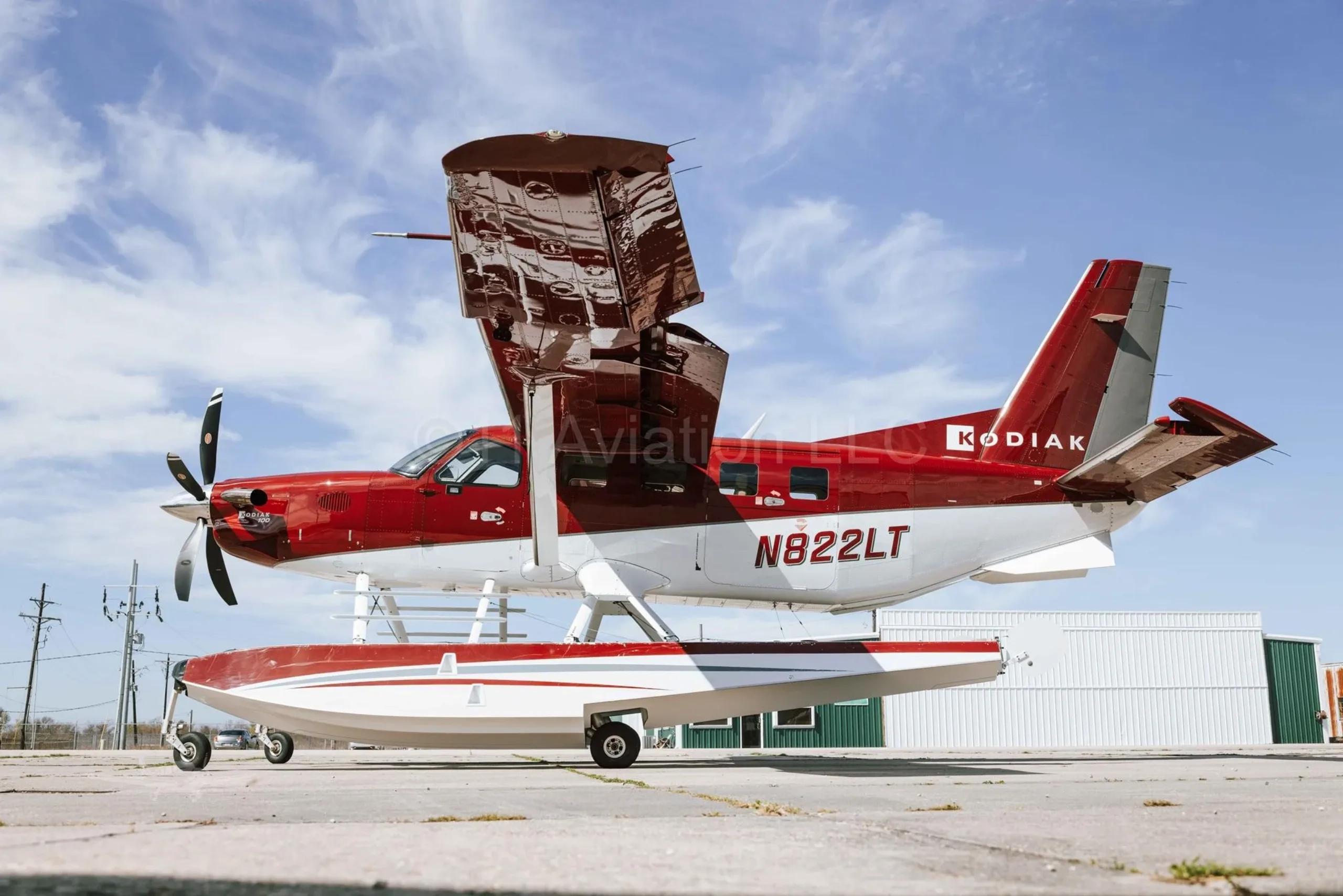 A red and white Kodiak aircraft on floats with the cargo door open.