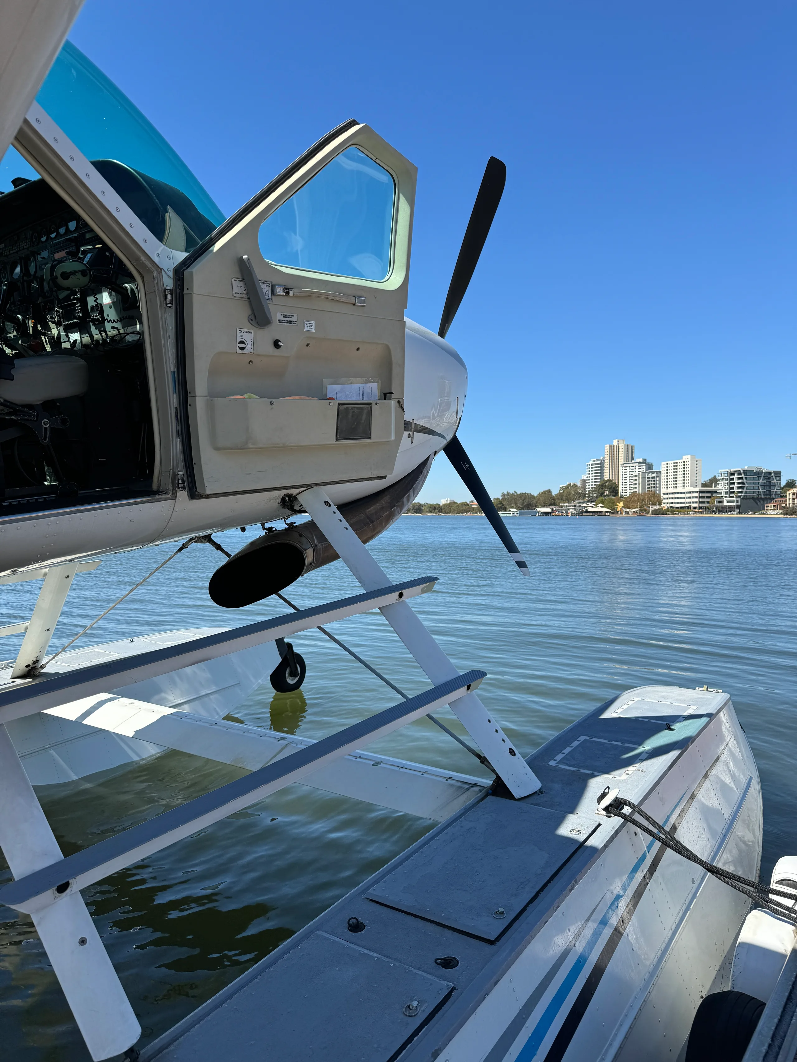 Close-up of a seaplane on the water with the door open, showing the engine and steps.