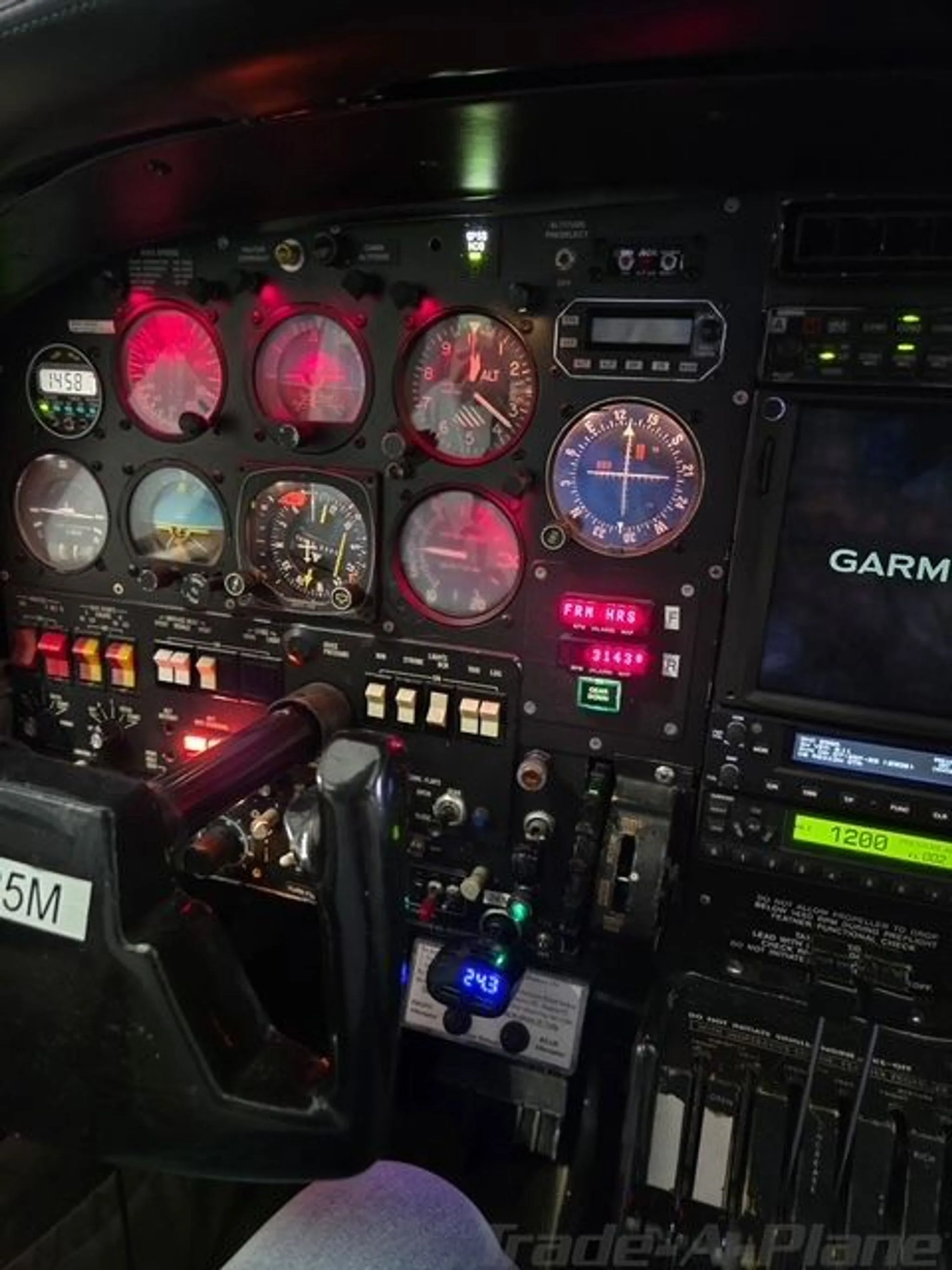 A detailed view of the aircraft's instrument panel, including the yoke, red-lit analog gauges, and digital screens.
