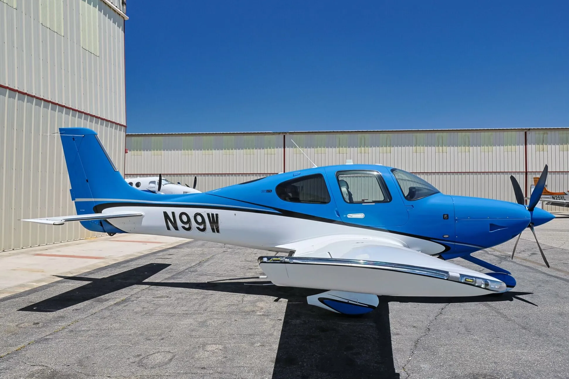 A blue and white Cirrus SR22 aircraft (N99W) parked on an airfield.