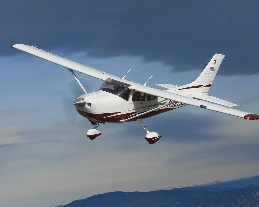 Cessna 182 Skylane in flight with a red and white paint scheme.