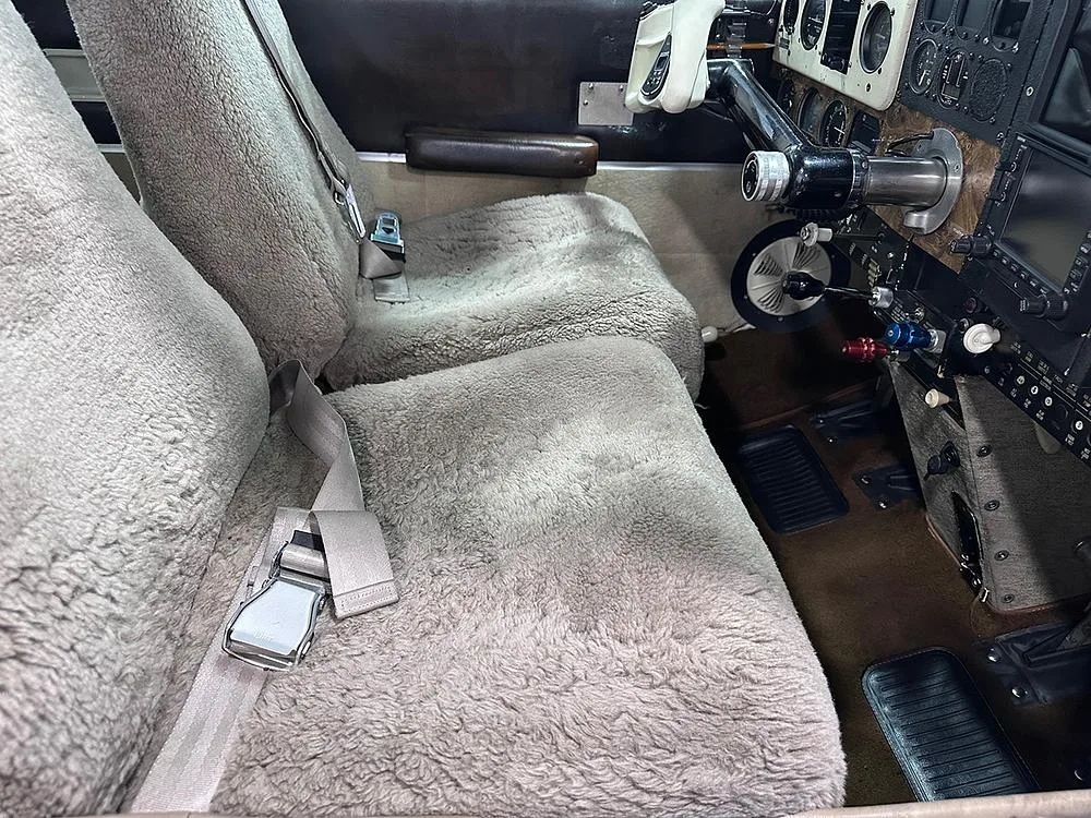 Interior view of an aircraft cabin with two front seats covered in light brown sheepskin.
