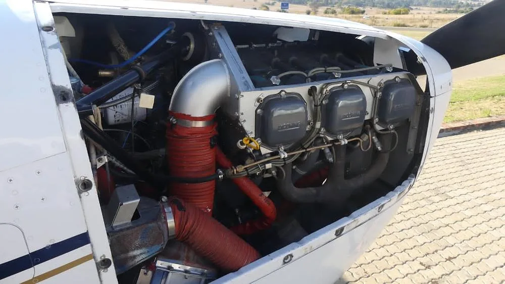 A close-up view of the aircraft's engine with red hoses and silver components visible.