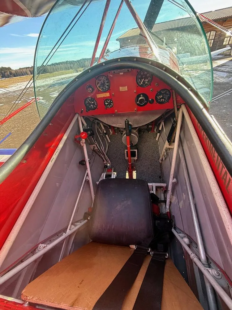 The cockpit of a Pitts Special biplane, showing the instrument panel, control stick, and single seat.