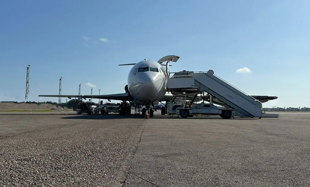 A front view of a UniWorld Air Cargo Boeing 727-200F parked on the tarmac with mobile stairs.