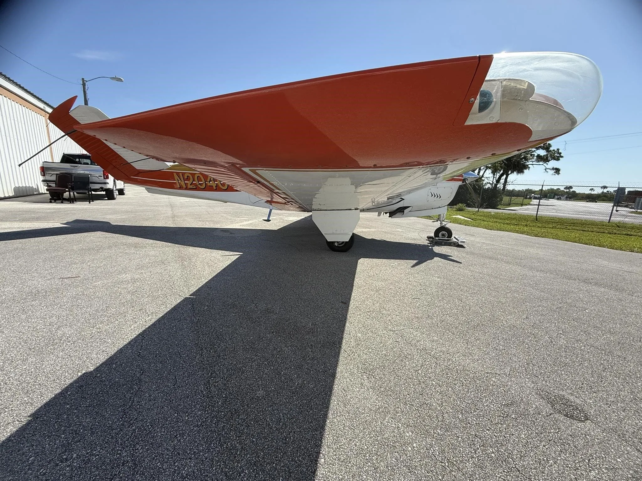 A low-angle view of the right wing and fuselage of a white and orange single-engine aircraft, N2040Y.