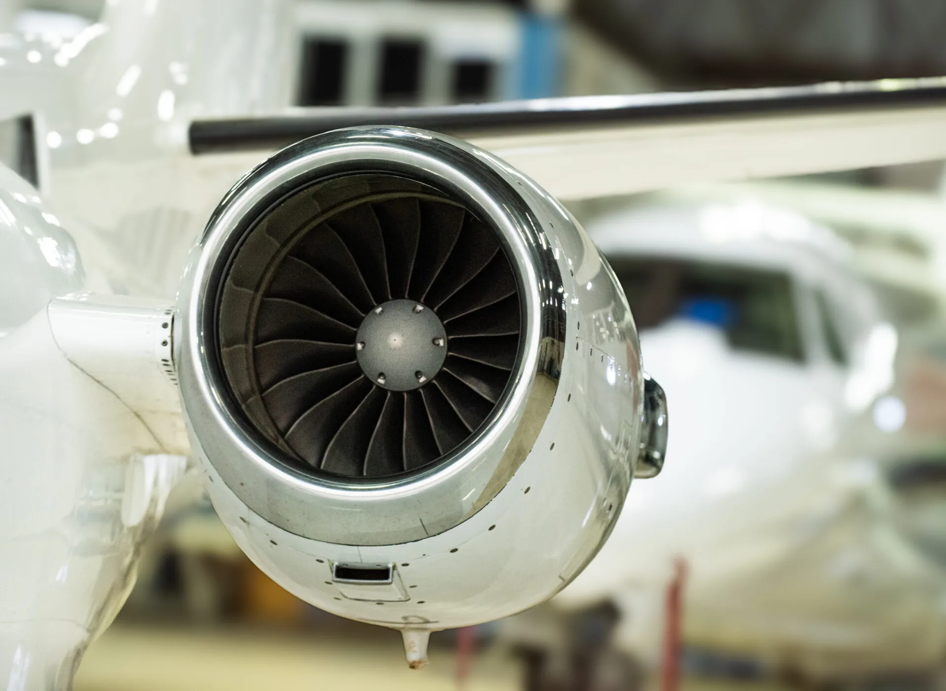 A close-up view of a jet engine on a white aircraft, showing the fan blades.