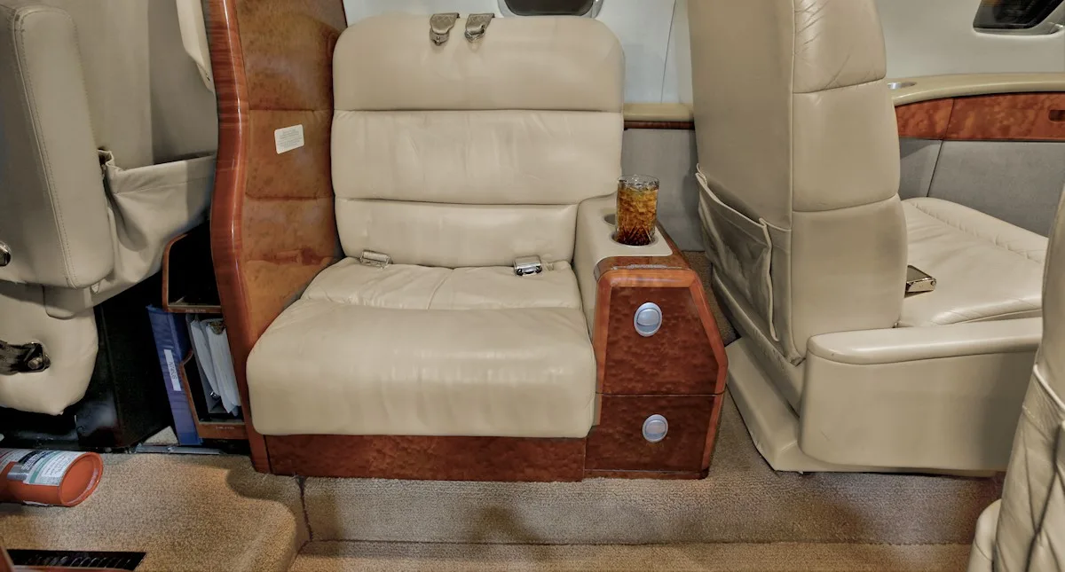 Aircraft interior with a tan leather seat and wood accents.