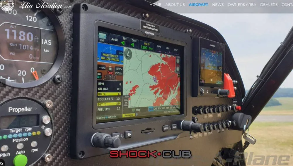 A close-up of the Zlin Shock Cub's cockpit instrument panel, featuring a Garmin display with a map and flight information.