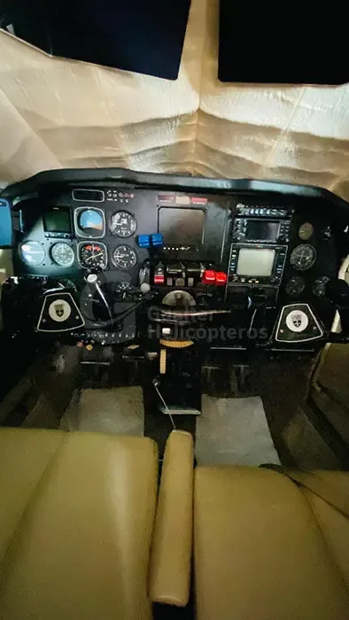 A full view of the aircraft cockpit from the passenger perspective, showing the instrument panel and pilot seats.